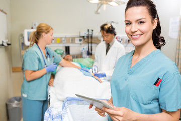 Nurse With Digital Tablet While Doctor And Colleague Operating P