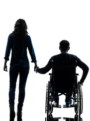 handicapped man in wheelchair  and woman holding hands silhouett