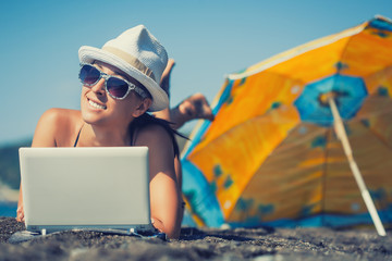 happy smiling girl is sunbathing with laptop