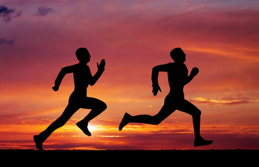 Fototapeta na wymiar Silhouettes of two runners on sunset fiery background