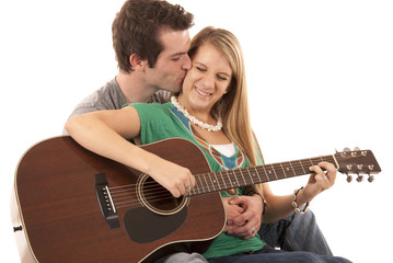 Young couple in love sitting playing guitar kissing