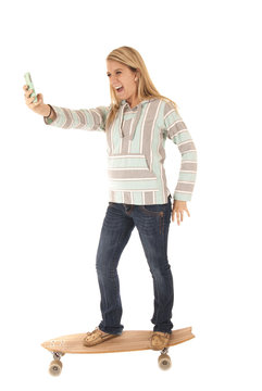Young girl on skateboard taking picture of herself smiling