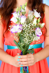 Woman holding bouquet, on blue background, close-up