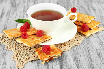 Cup of tea with cookies and raspberries on table close-up