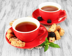 Cups of tea with cookies and blackberry on table close-up