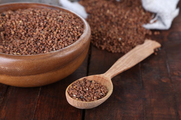 Buckwheat groats in bowl and  wooden spoon closeup