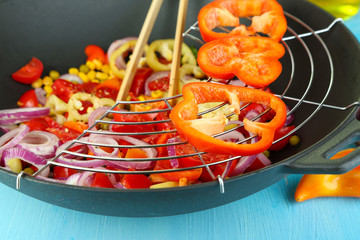 Vegetables in wok on wooden table close-up