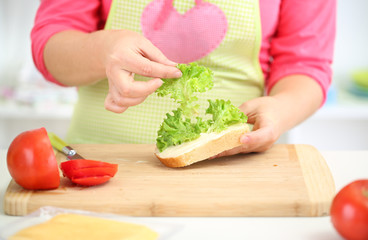 Happy smiling woman in kitchen preparing  sandwich, close up