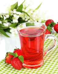 Delicious strawberry tea on table on white background