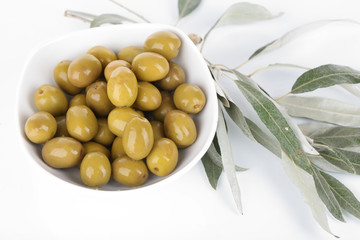 Olives in bowl with branch isolated on white