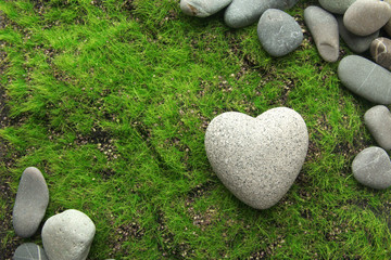 Grey stone in shape of heart, on grass background