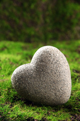 Grey stone in shape of heart, on grass background