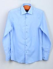 Male shirt on wooden hanger on wall background