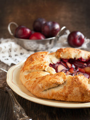 Fresh homemade plum galette on wooden table. Selective focus
