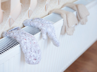 Knitted gloves drying on heating radiator