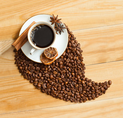 A cup of coffee and coffee beans on wooden surface