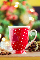 Tea cup with paper Christmas tree over bokeh background