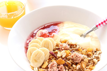 Granola, banana, yoghurt and raspberry jam for healthy breakfast