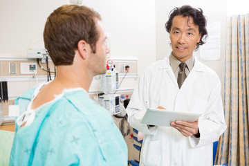 Doctor Holding Digital Tablet By Patient In Hospital