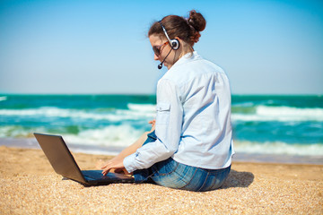 Business woman talking using her laptop on the beach