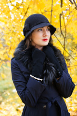 Woman in a black hat on background of autumn tree