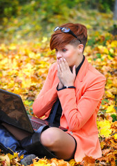 Fototapeta na wymiar Cute woman with laptop in the autumn park