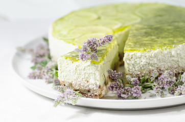 Lime cheesecake decorated with mint flowers, blurred background