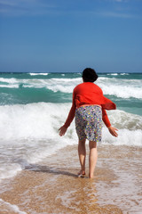 Fototapeta na wymiar Happy woman stands in the sea beach