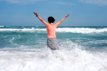 Happy woman stands in the sea beach