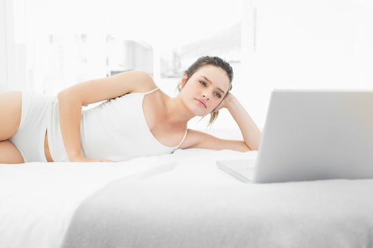 Casual woman looking at laptop in bed