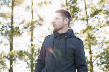 Man in pullover standing in forest against trees