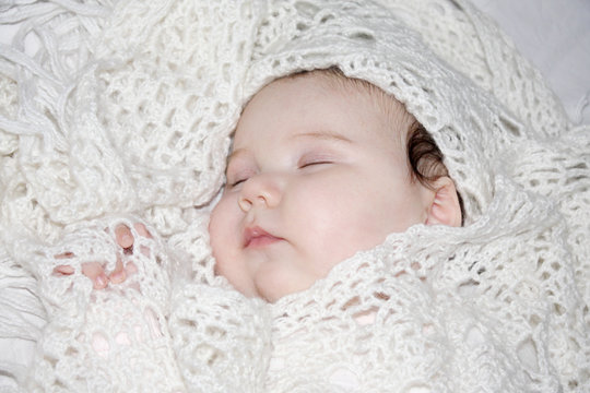 Little beautiful sleeping baby lies in knitted shawls