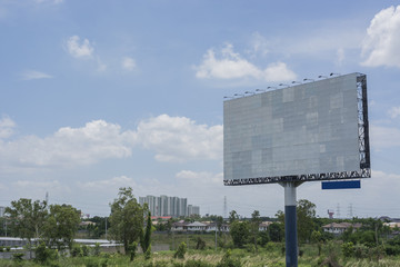 Billboard with empty screen, against blue cloudy sky