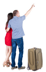 young couple traveling with suitcas and pointing at wal Back vie