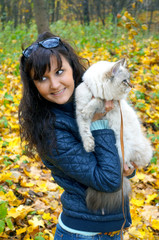 Young woman and  siberian cat in a autumn forest