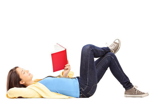 Young female student lying on a floor and reading a novel