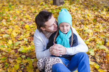 Young father have fun with his cute daughter in autumn park at