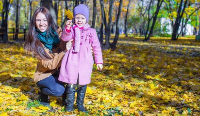 Little girl with young mother in yellow autumn park on a warm