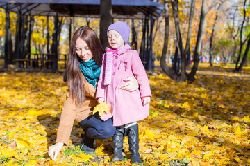 Happy mother and her adorable daughter walking in yellow autumn