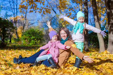 Little girls and young mother in autumn park have fun