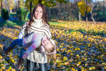 Fototapeta premium Little adorable girl and young mother in autumn park on sunny