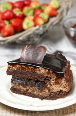 Chocolate cake and basket of fresh raw strawberries in the backg