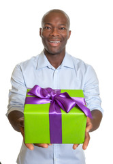 Laughing african man showing a gift for christmas