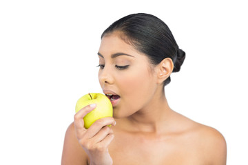 Obraz na płótnie Canvas Calm nude brunette eating green apple