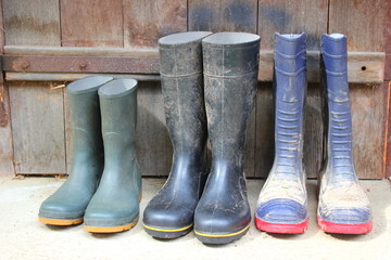 Die Gummistiefel einer Familie vor einer Stalltür