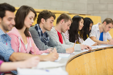 Students writing notes in a row at the lecture hall
