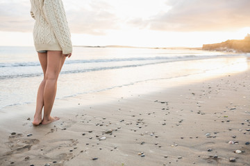 Low section of a woman in sweater standing on beach