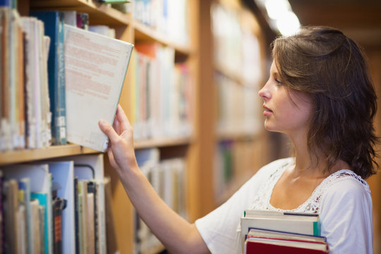 Female student selecting book in the library