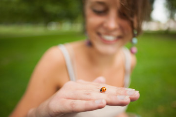 Close-up of a blurred woman gently holding a ladybug