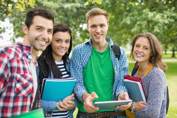 Portrait of college students with bags and books in park